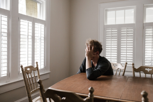 a man looking out the window in the dining room of a white painted house